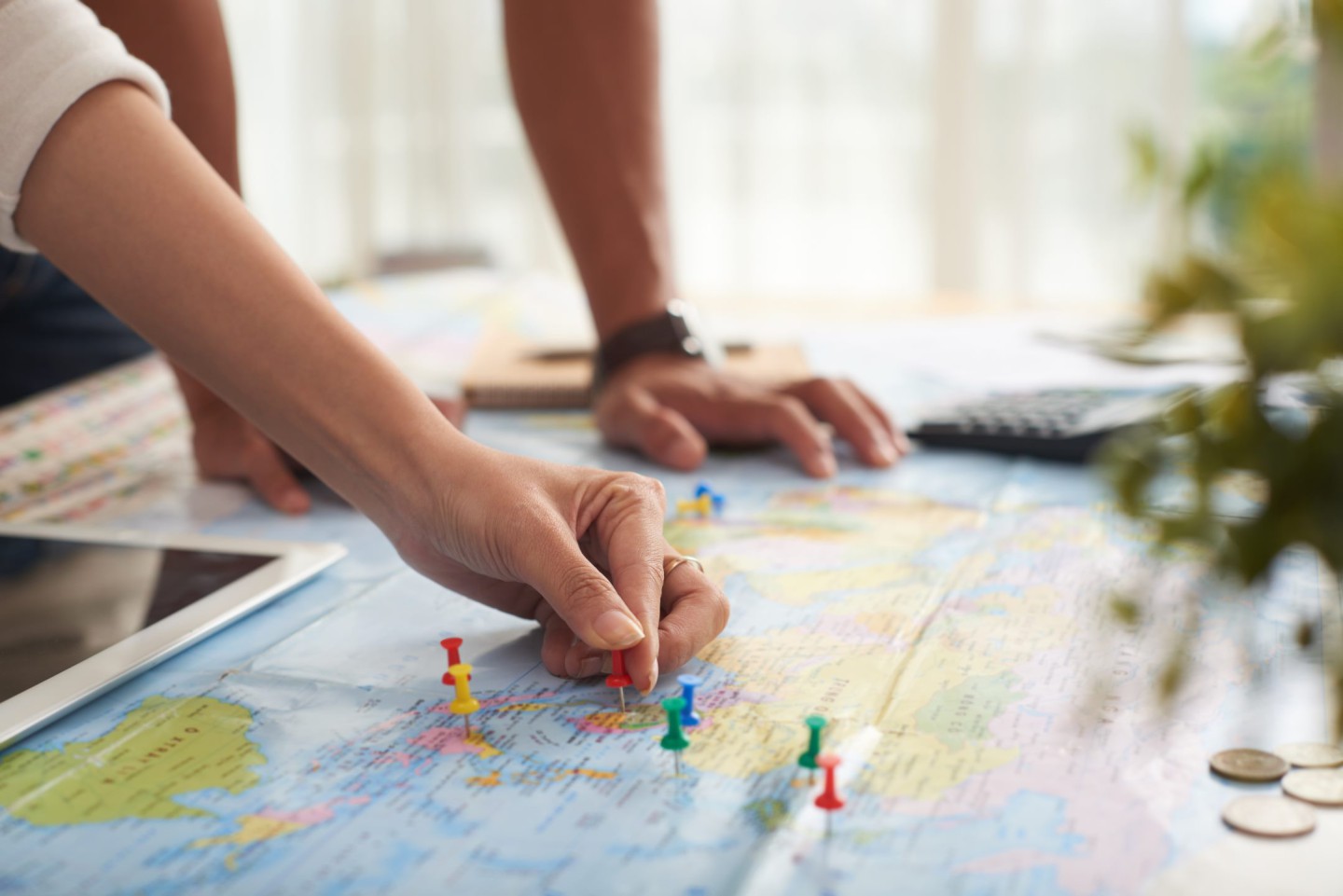 Two hands placing pins on a world map